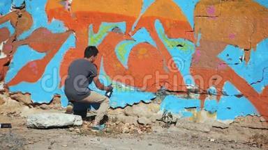 涂鸦艺术家在街墙上画画。 帅气的男人用喷雾瓶喷着五颜六色的油漆，城市
